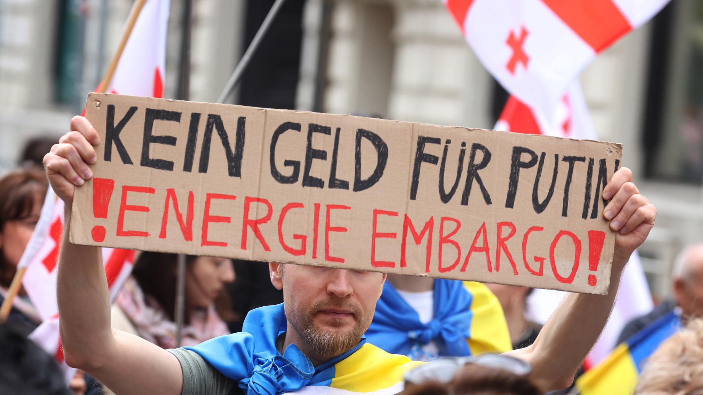 Ein Teilnehmer einer Kundgebung gegen den Krieg in der Ukraine hält bei einem Demonstrationszug durch die Innenstadt ein Schild mit der Aufschrift "Kein Geld für Putin! Energie Embargo!".