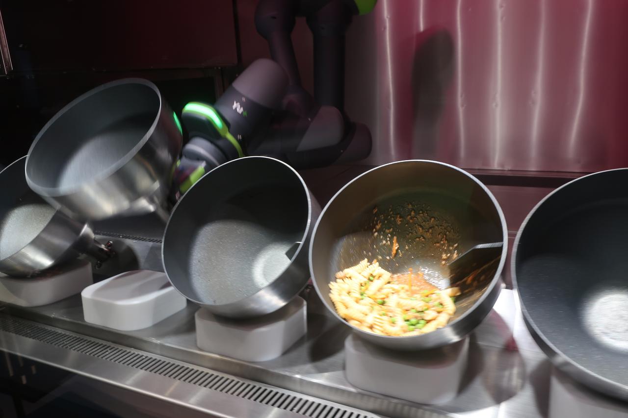 Roboter Koch beim Kochen. Zu sehen sind viele Schüsseln, in einer befinden sich Zutaten. Roboter Koch beim Kochen. Zu sehen sind viele Schüsseln, in einer befinden sich Zutaten.