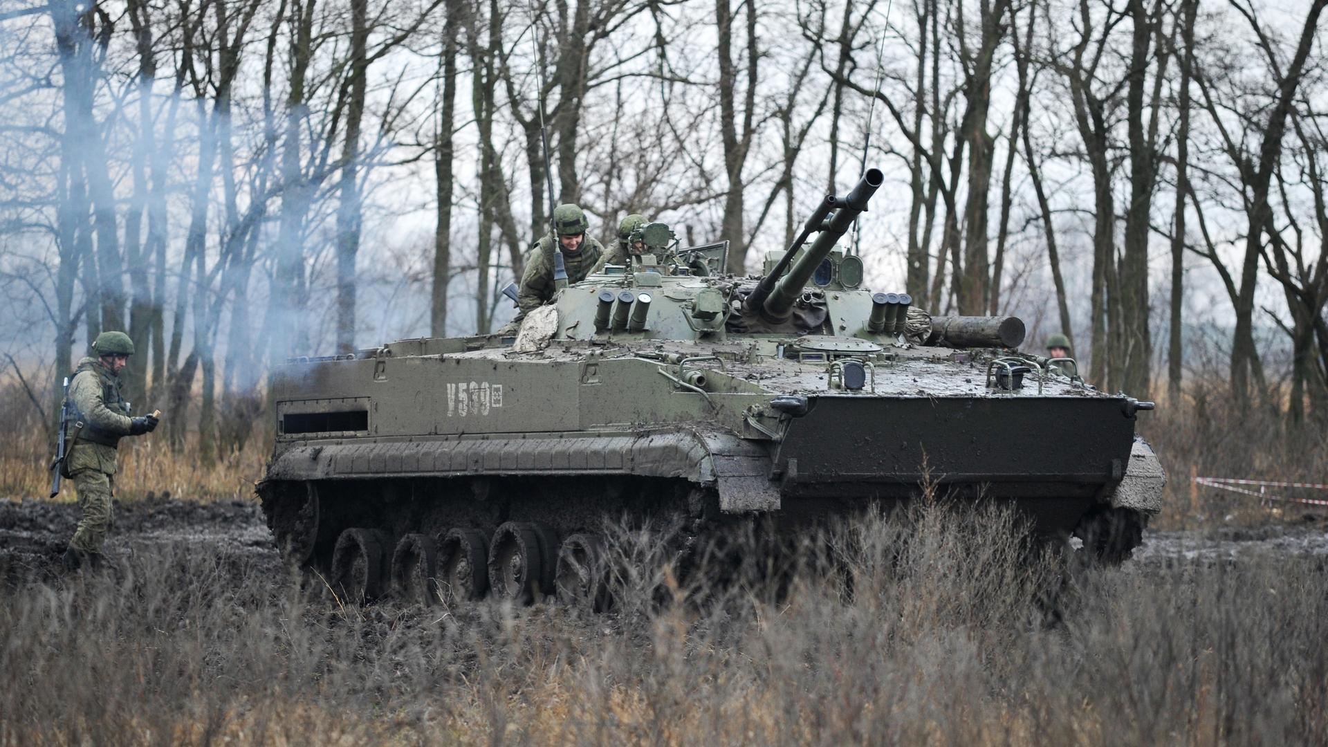 Ein Panzer und drei Soldaten bei einer Militärübung.