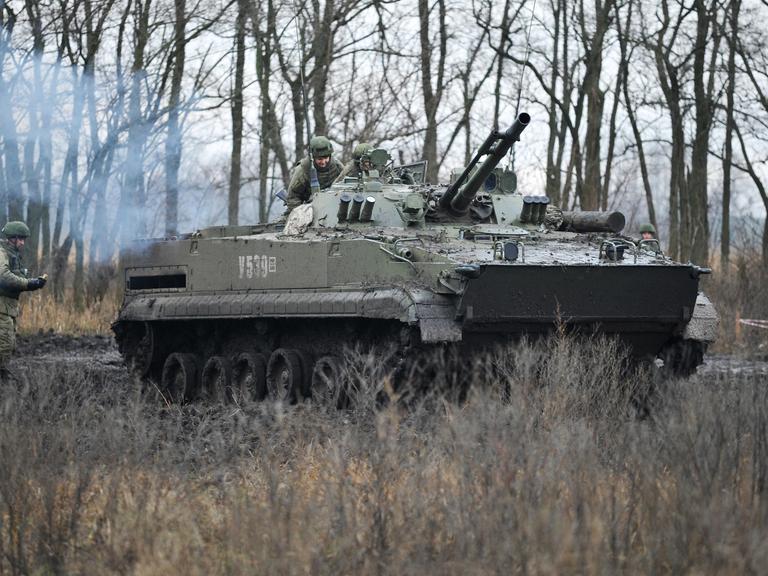 Ein Panzer und drei Soldaten bei einer Militärübung.