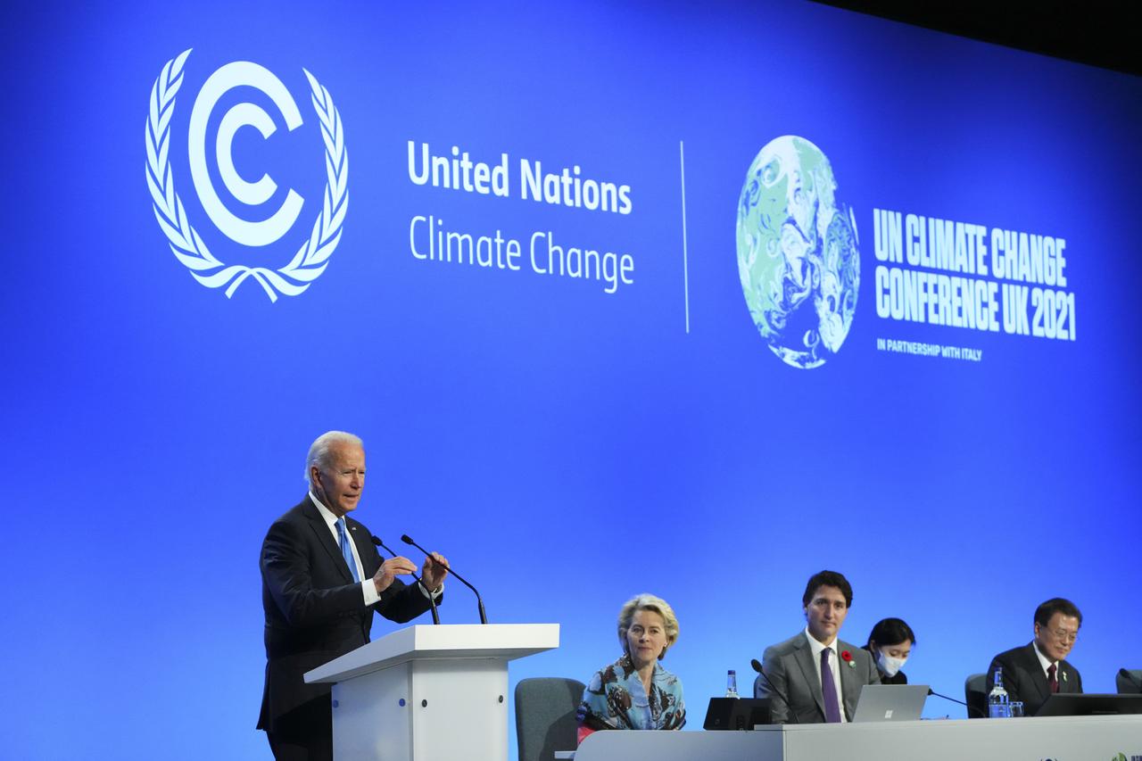 US-Präsident Joe Biden in blauem Anzug spricht auf einem Konferenzpanel in ein Mikro, blauer Hintergrund US-Präsident Joe Biden in blauem Anzug spricht auf einem Konferenzpanel in ein Mikro, blauer Hintergrund