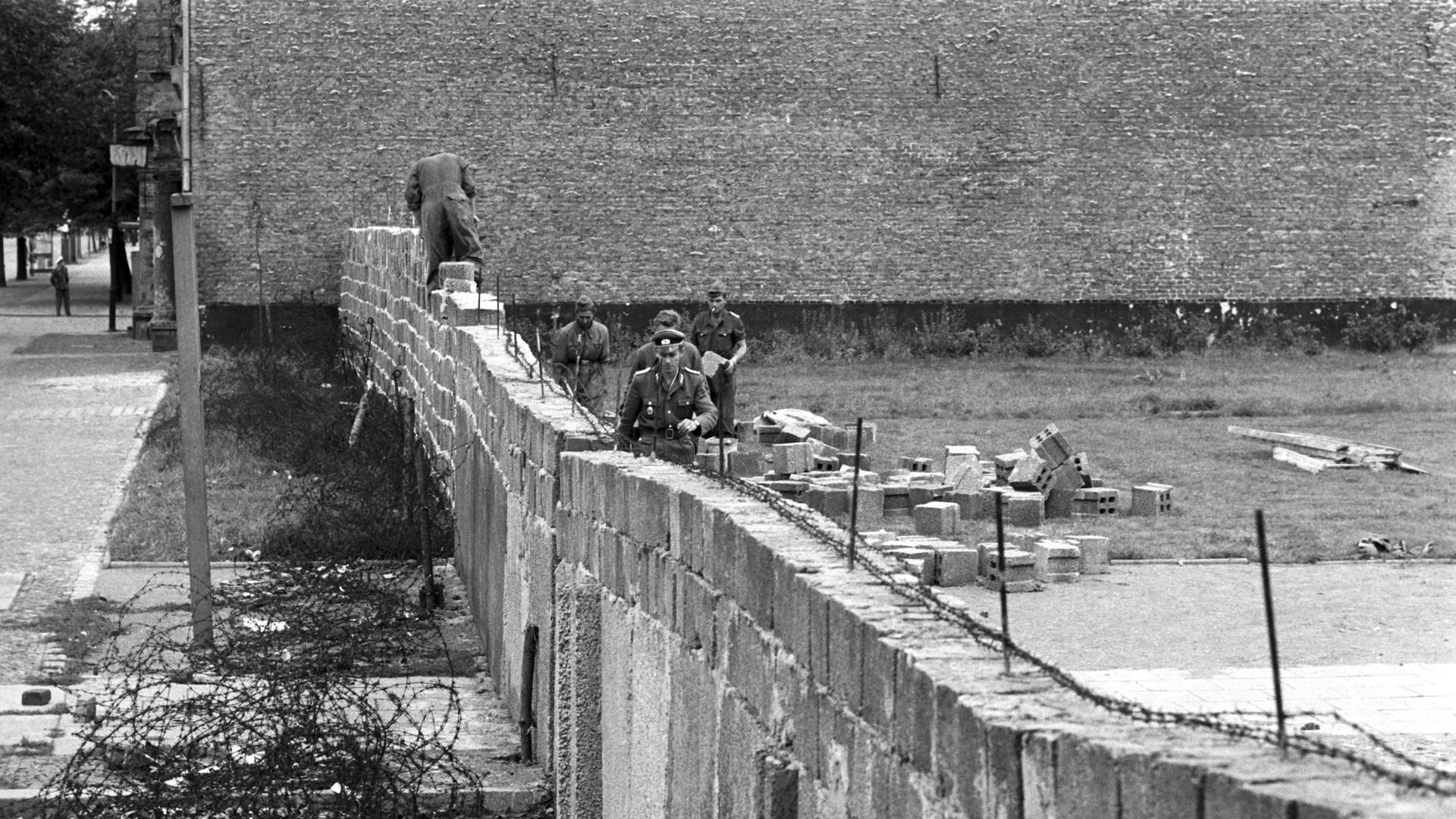 Volkspolizisten und Arbeiter der DDR beim Errichten der Berliner Mauer am 6.10.1961 im Norden Berlins, an der Grenze zum westberliner Bezirk Reinickendorf. 