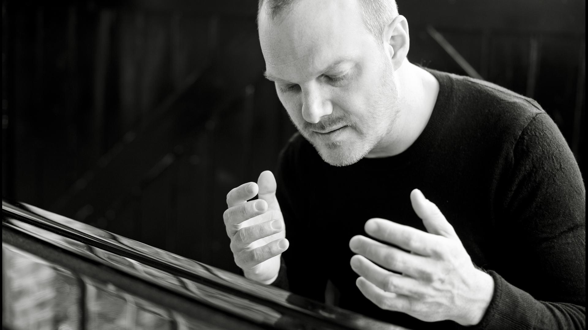 Der Pianist Lars Vogt sitzt am Flügel und hat beide Hände in einer Musikpause erhoben und genießt den Augenblick mit geschlossenen Augen. Der Pianist Lars Vogt sitzt am Flügel und hat beide Hände in einer Musikpause erhoben und genießt den Augenblick mit geschlossenen Augen.