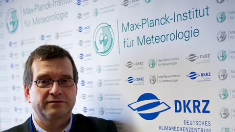 Jochem Marotzke steht vor einem Schild mit dem Schriftzug "Max-Planck-Institut für Meteorologie".