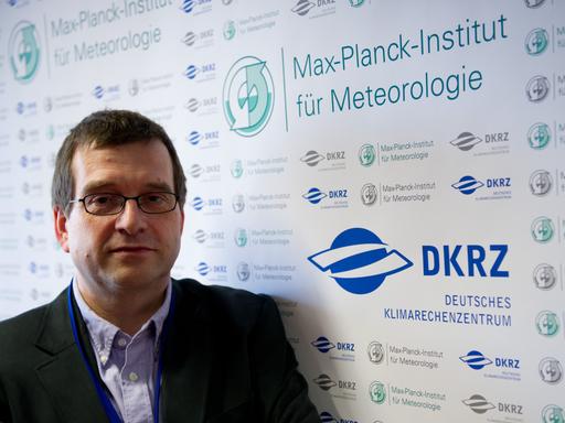 Jochem Marotzke steht vor einem Schild mit dem Schriftzug "Max-Planck-Institut für Meteorologie".