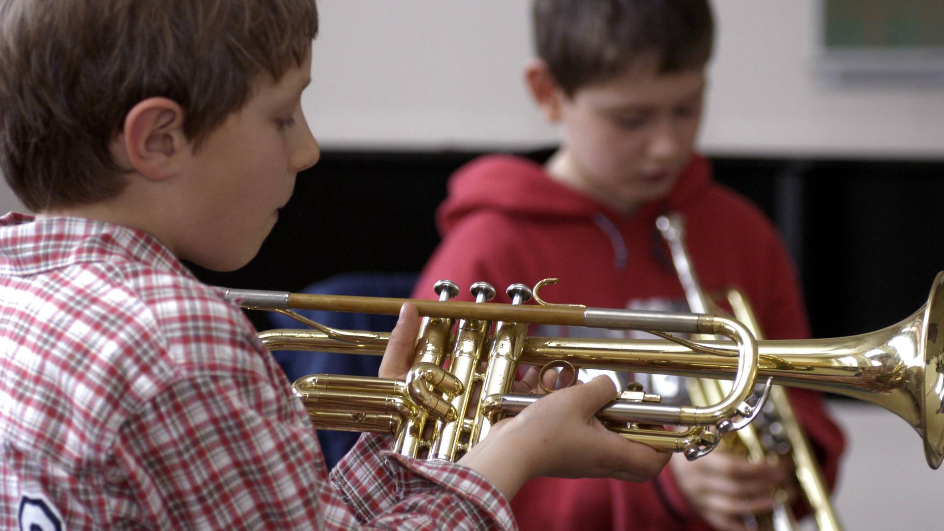 Zwei Jungs probieren und spielen Trompete in einer Musikschule.