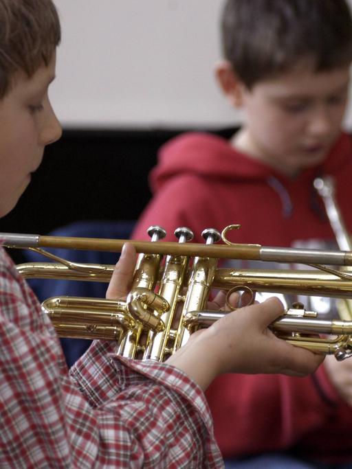 Zwei Jungs probieren und spielen Trompete in einer Musikschule.