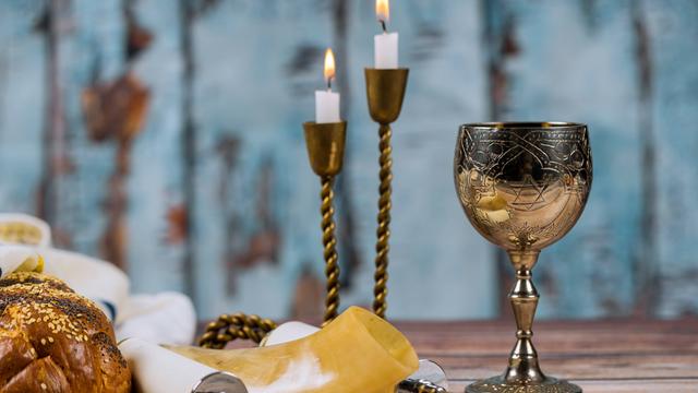 Ein Weinkelch, Kerzen, ein Horn, eine Schriftrolle und ein Laib Brot