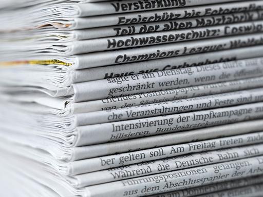 Ein Stapel mit verschiedenen Tageszeitungen liegt auf einem Tisch.