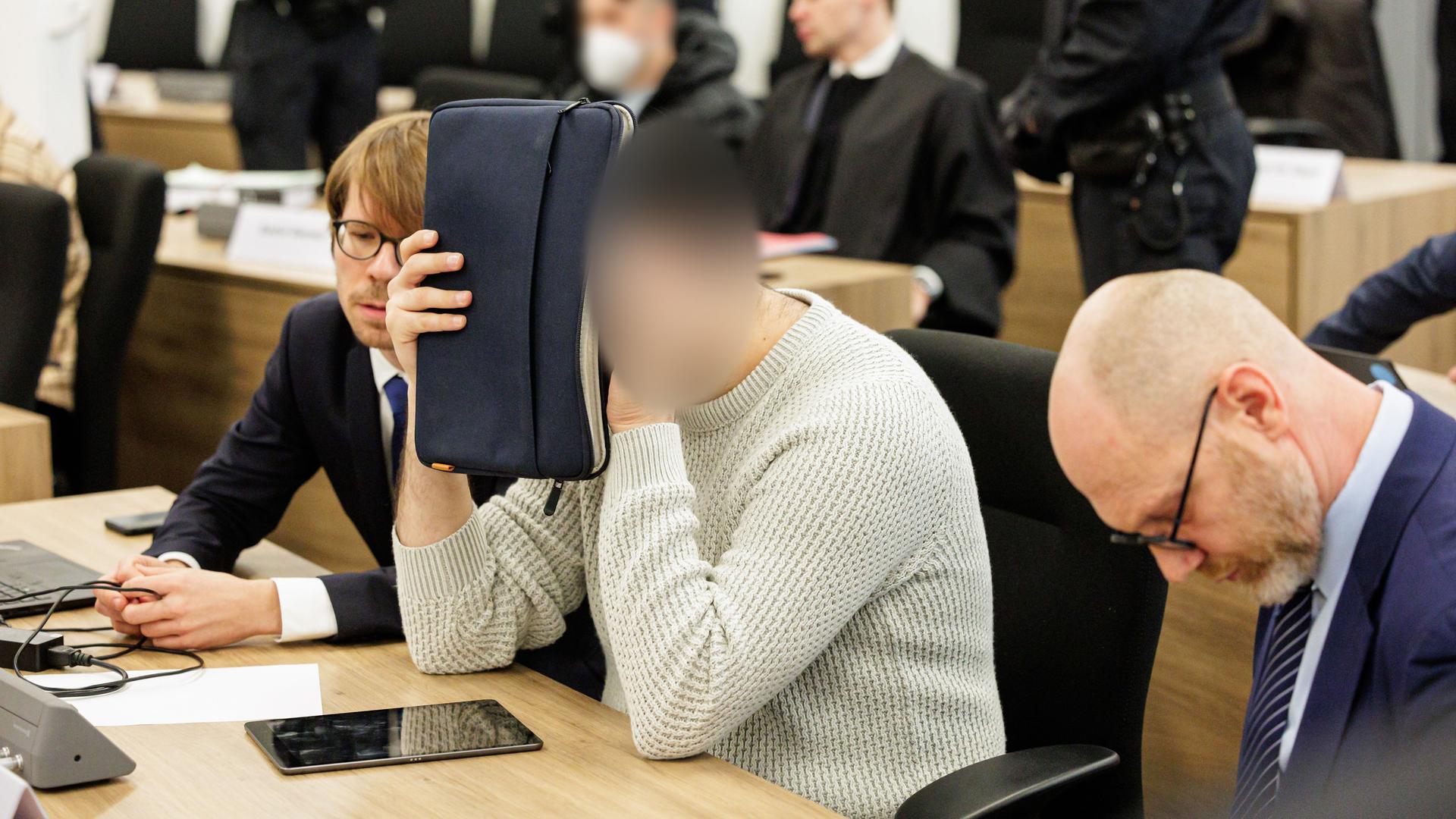 Dresden: Ein Angeklagter (M) bedeckt sein Gesicht im Gerichtssaal des Oberlandesgerichts Dresden, bevor der Prozess um den Juwelenraub im Grünen Gewölbe des Dresdner Residenzschlosses im November 2019 beginnt. Dresden: Ein Angeklagter (M) bedeckt sein Gesicht im Gerichtssaal des Oberlandesgerichts Dresden, bevor der Prozess um den Juwelenraub im Grünen Gewölbe des Dresdner Residenzschlosses im November 2019 beginnt.