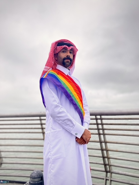 Nas Mohamedin traditionellem katarischem gewand mit einer Regenbogenschärpe. Nas Mohamedin traditionellem katarischem gewand mit einer Regenbogenschärpe.