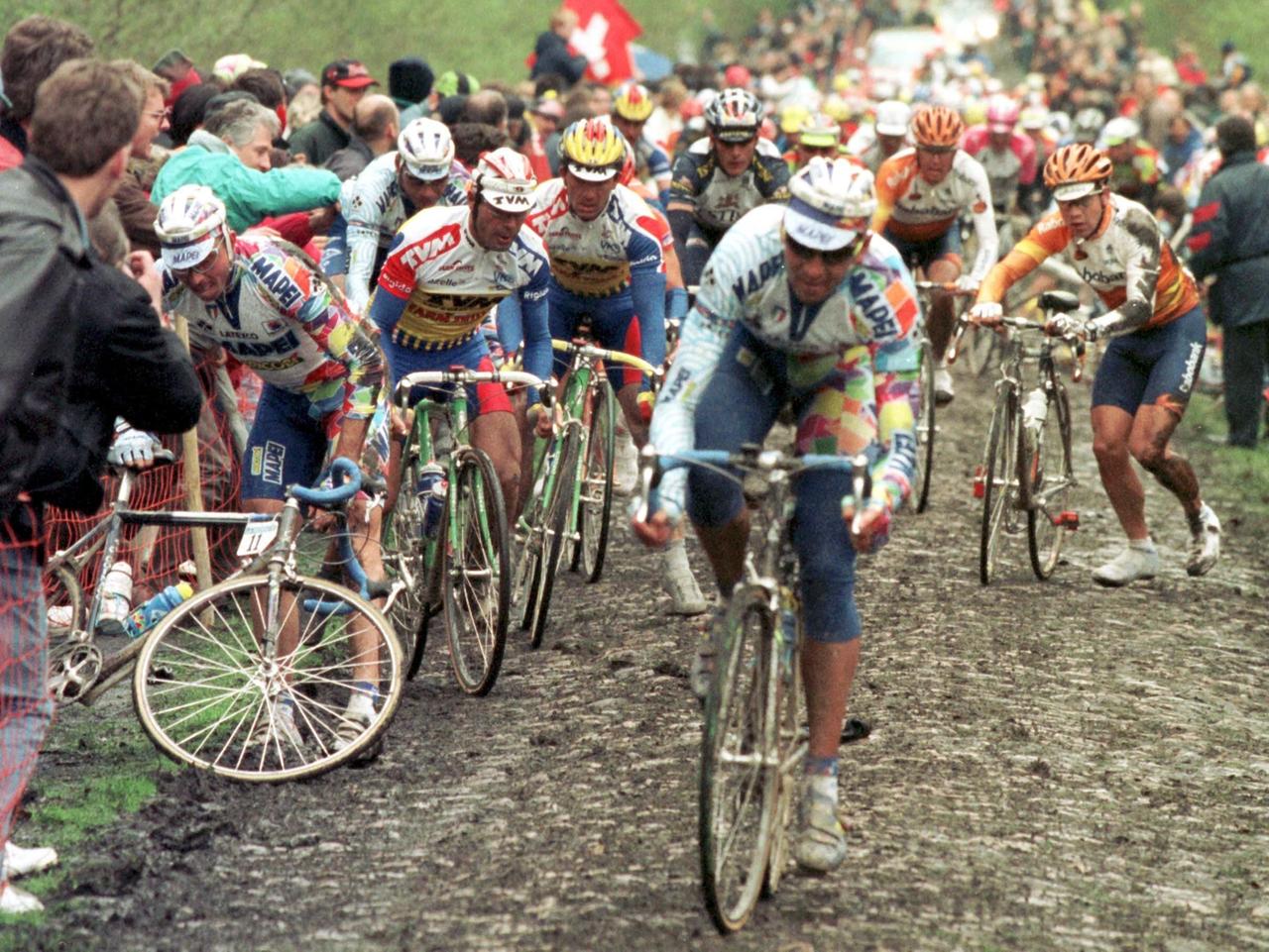 Stürzend und schiebend passiert eine Gruppe von Fahrern einen schlammigen Kopfsteinpflaster-Feldweg beim Frühjahrs-Klassiker Paris - Roubaix. Stürzend und schiebend passiert eine Gruppe von Fahrern einen schlammigen Kopfsteinpflaster-Feldweg beim Frühjahrs-Klassiker Paris - Roubaix.