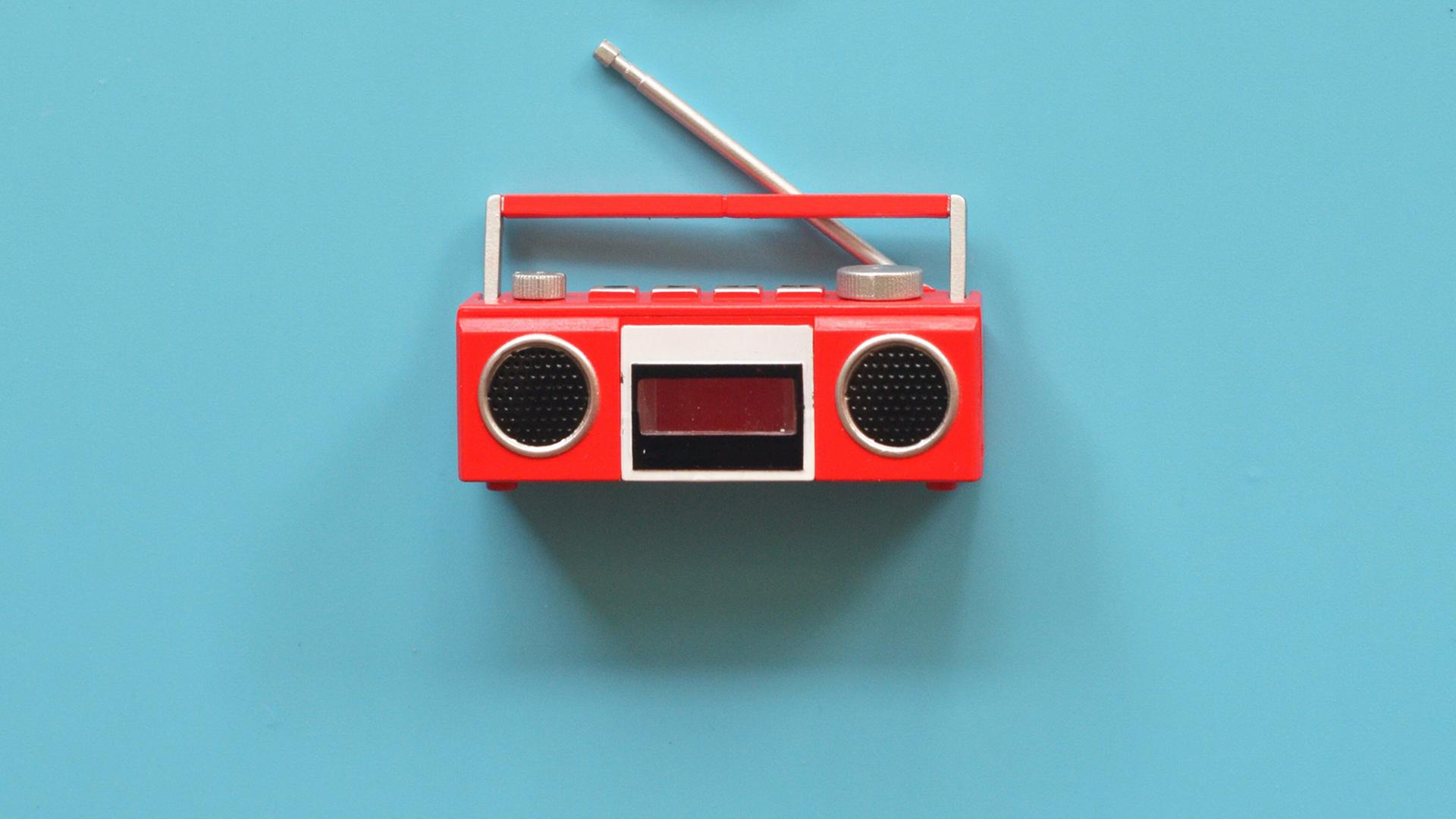 Ein rotes radio aus den 1970er Jahren vor blauem Hintergrund. Ein rotes radio aus den 1970er Jahren vor blauem Hintergrund.