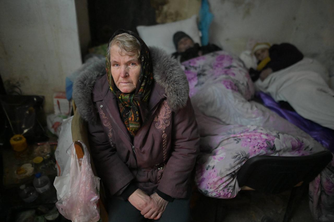 Eine alte Frau mit Kopftuch in einem Keller in Mariupol, wo die Menschen Schutz vor den Bombardierungen suchen.  