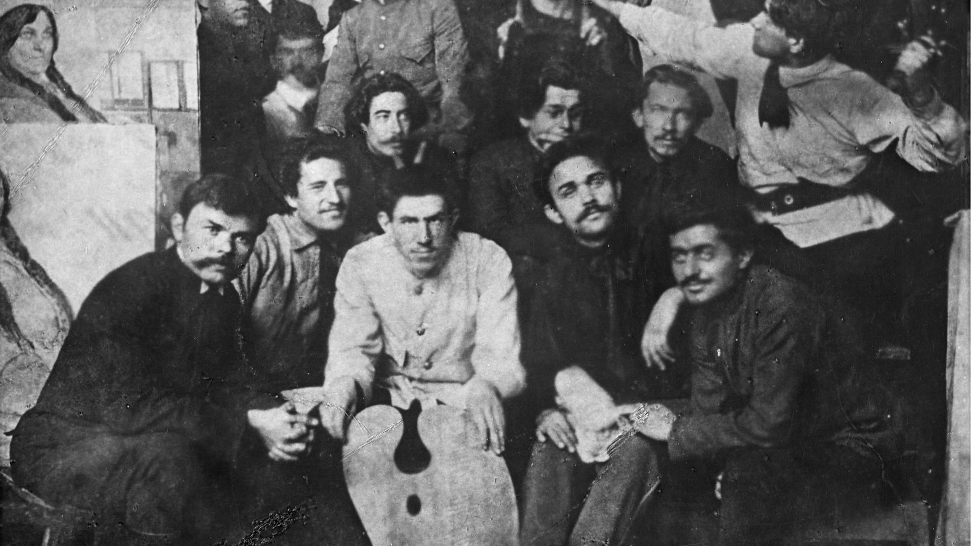 Wladimir Wladimirowitsch Majakowski sitzt umringt von Kollegen und posiert für ein Gruppenfoto. Wladimir Wladimirowitsch Majakowski sitzt umringt von Kollegen und posiert für ein Gruppenfoto.