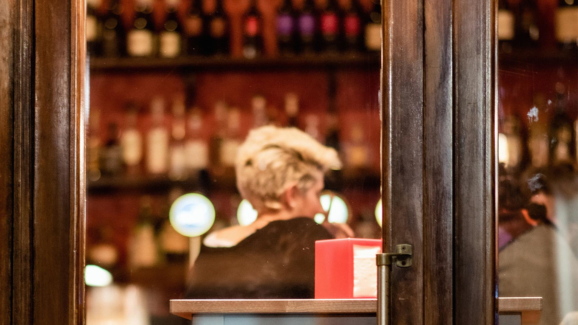 Blick in den Gastraum eines Cafés. Am Tisch sitzt eine junge, blonde Frau mit dem Rücken zur Kamera. Blick in den Gastraum eines Cafés. Am Tisch sitzt eine junge, blonde Frau mit dem Rücken zur Kamera.