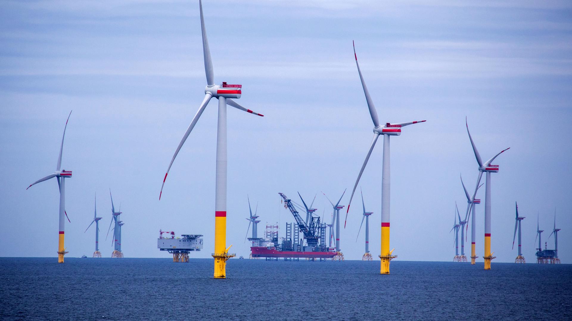 Ein Arbeitsschiff steht auf Stelzen zwischen Windrädern, die in der Ostsee zwischen den Inseln Rügen und Bornholm (Dänemark) errichtet wurden. Ein Arbeitsschiff steht auf Stelzen zwischen Windrädern, die in der Ostsee zwischen den Inseln Rügen und Bornholm (Dänemark) errichtet wurden.