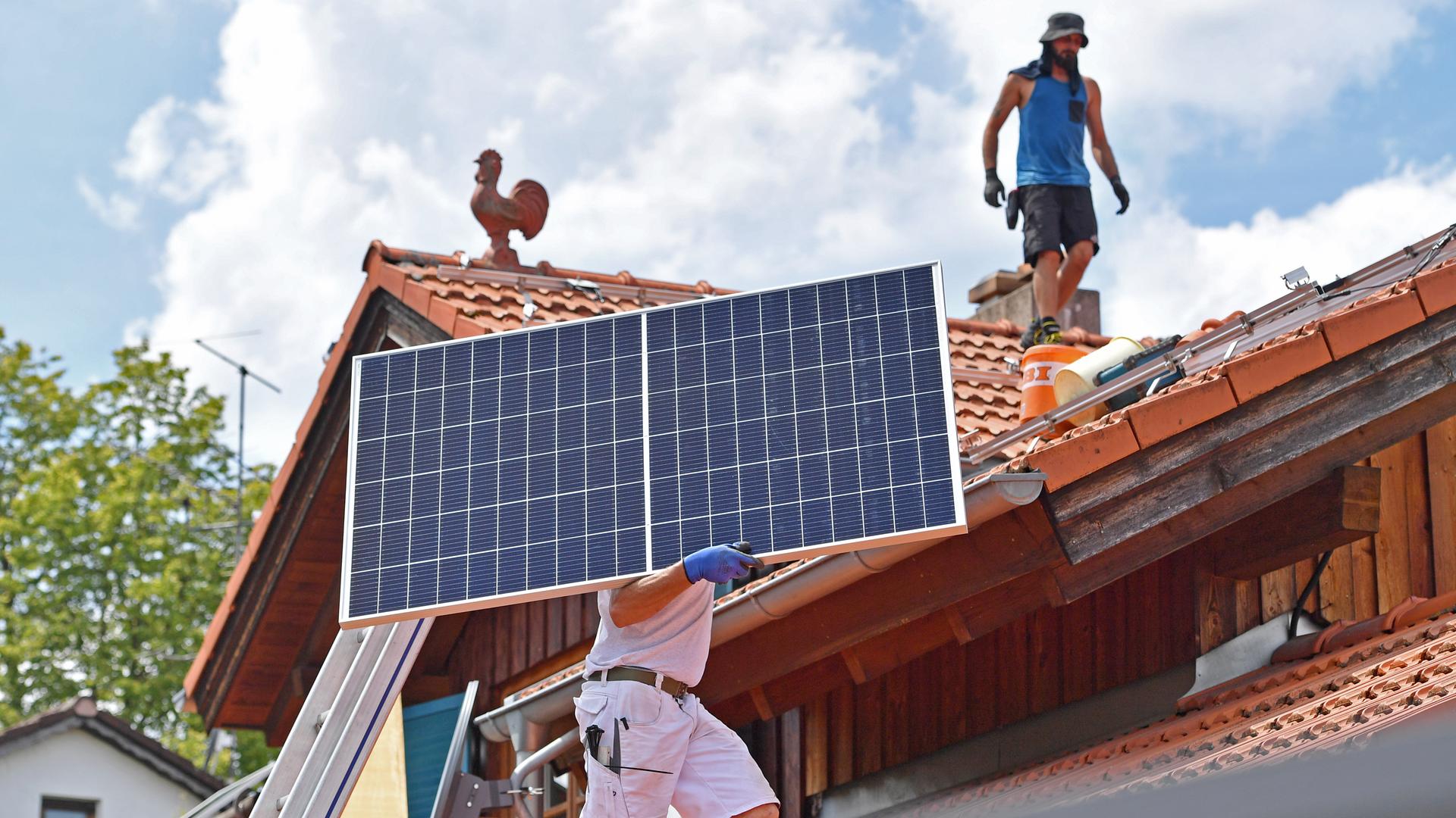 Solarmodule werden auf ein Hausdach transportiert. Solarmodule werden auf ein Hausdach transportiert.