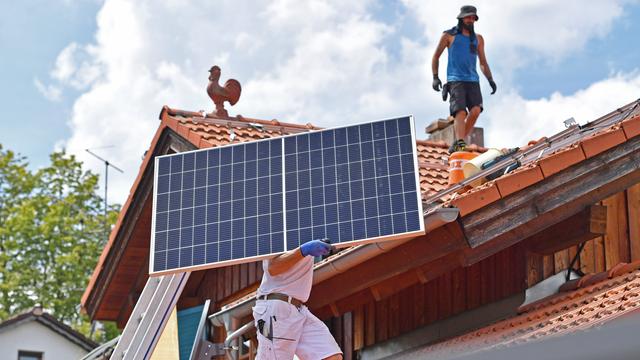 Solarmodule werden auf ein Hausdach transportiert.
