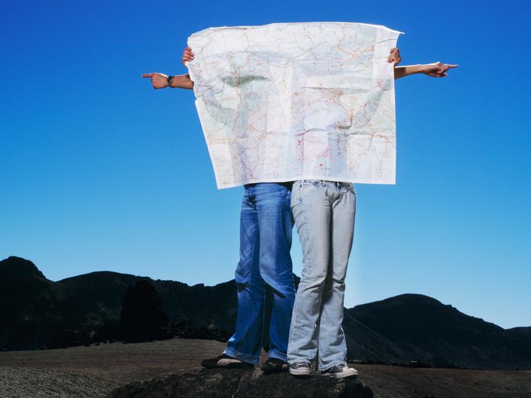 Ein Paar hinter einer Karte, das in verschiedene Richtungen möchte.