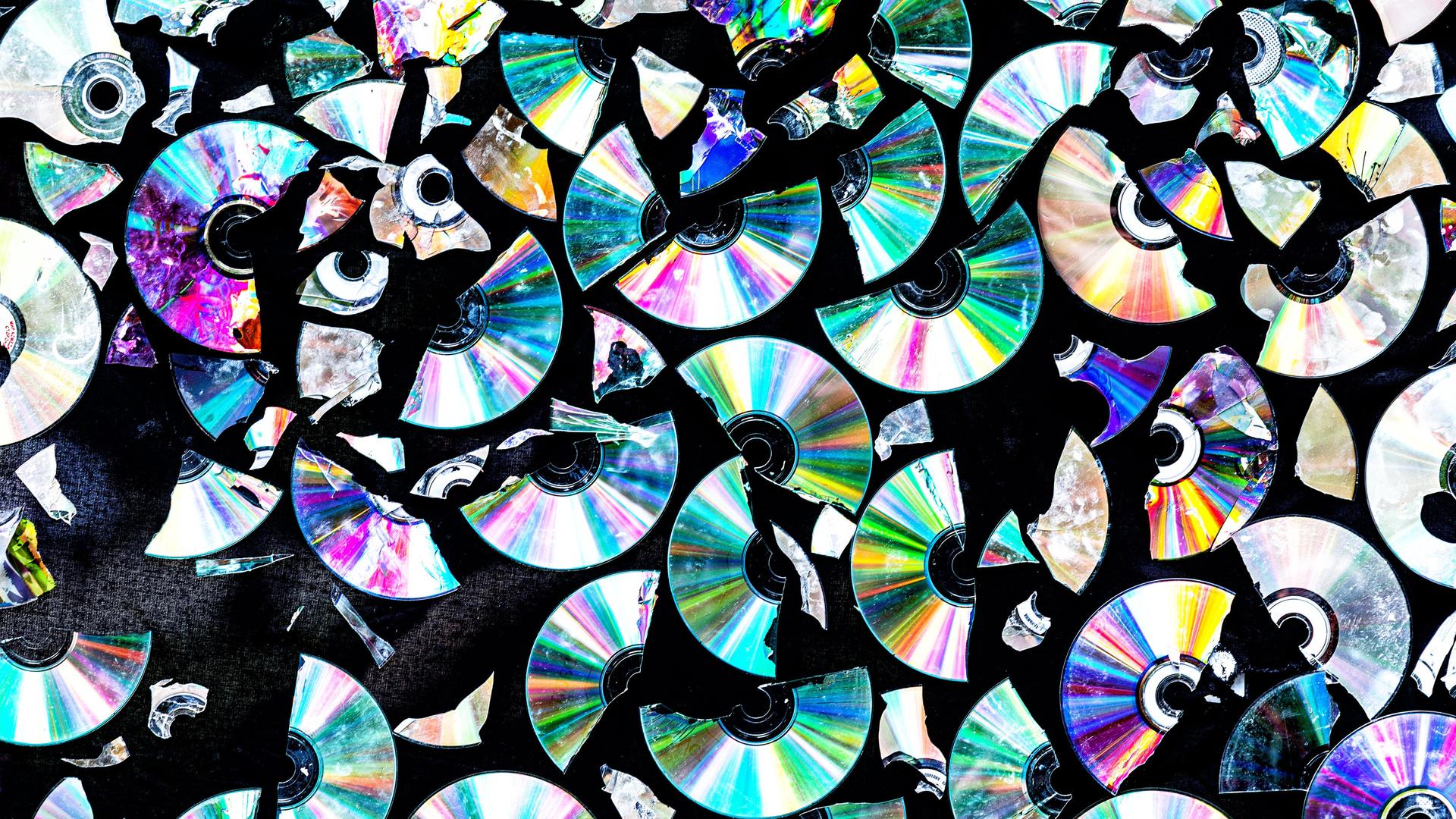 Silbrig glänzende CD-Scherben auf einem dunklen Hintergrund Silbrig glänzende CD-Scherben auf einem dunklen Hintergrund