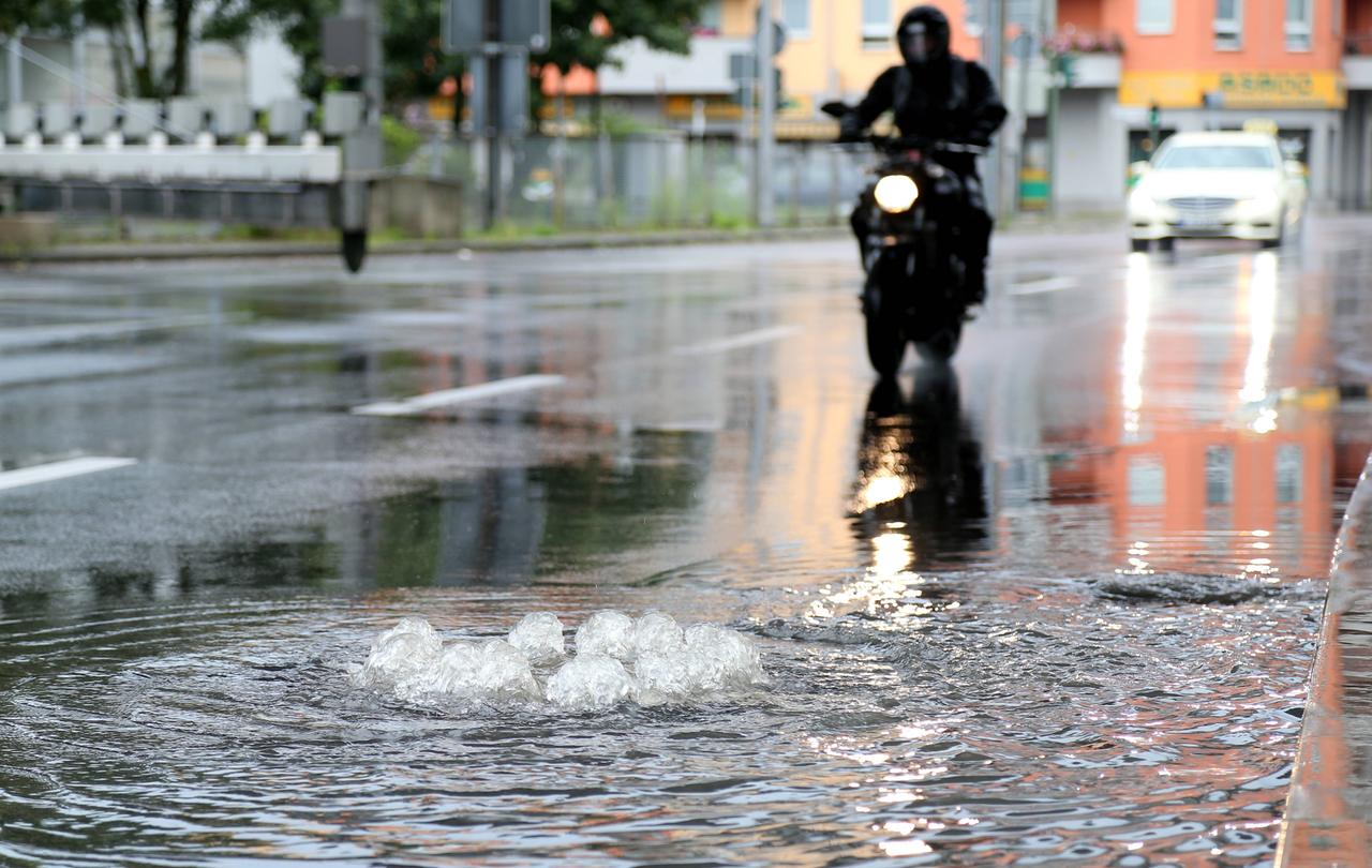 Sprudelnder Kanalisationsdeckel in Reinickendorf in Berlin nach Starkregen im Jahr 2017 Sprudelnder Kanalisationsdeckel in Reinickendorf in Berlin nach Starkregen im Jahr 2017