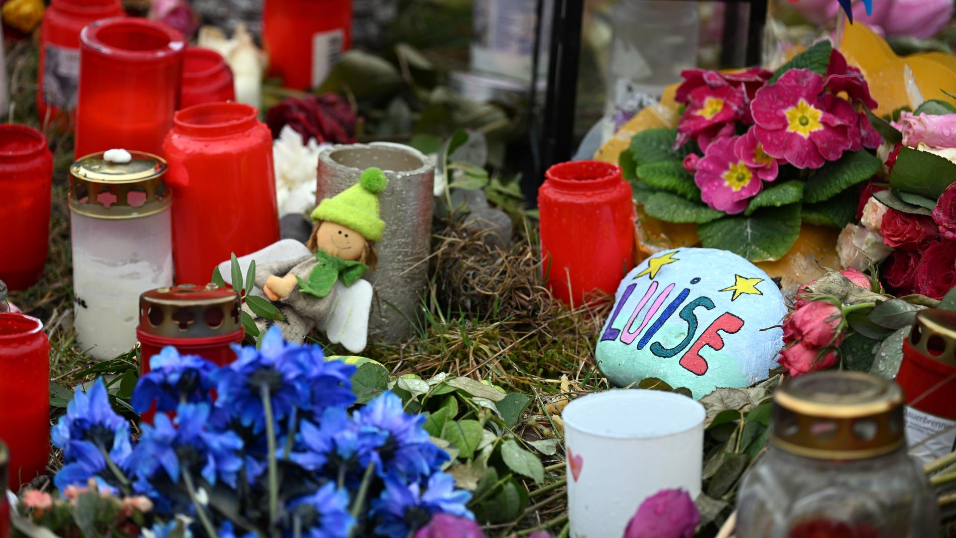Ein Holzkreuz, zahlreiche Blumen, Kuscheltiere und Kerzen liegen in Freudenberg in Gedenken an die zwölfjährige Luise am Tatort