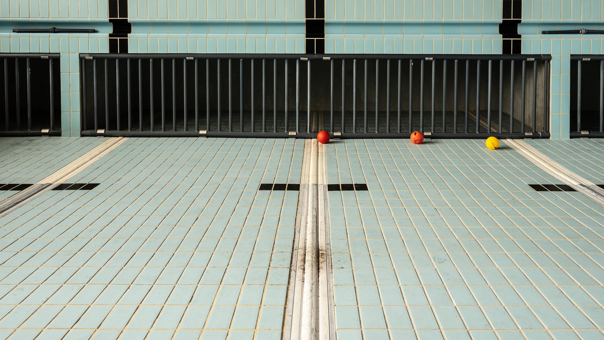 Ein leeres Schwimmbecken mit hellblauen Kacheln und schwarzen Linien.