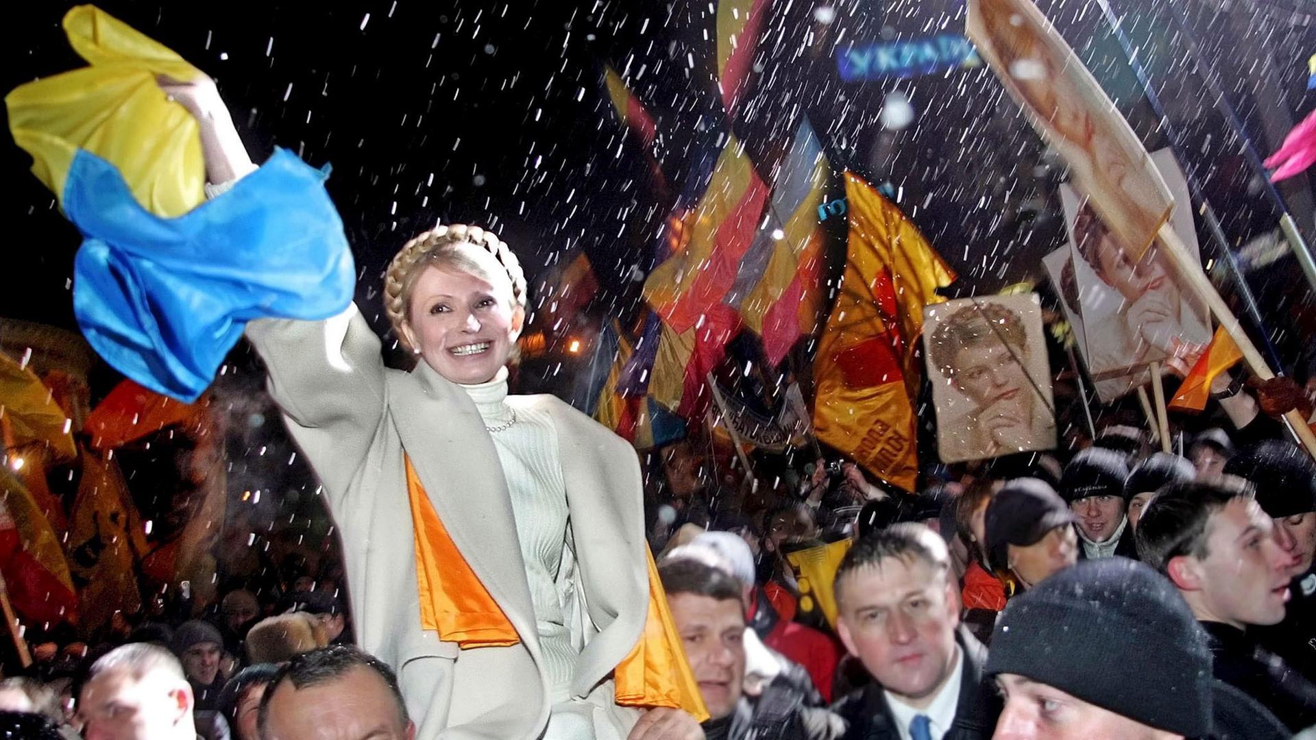 Die ehemalige Premierministerin der Ukraine, Julija Tymoschenko, wird am 22. November 2005 von ihren Anhängern über den Unabhängigkeitsplatz in Kiew getragen. Die ehemalige Premierministerin der Ukraine, Julija Tymoschenko, wird am 22. November 2005 von ihren Anhängern über den Unabhängigkeitsplatz in Kiew getragen.