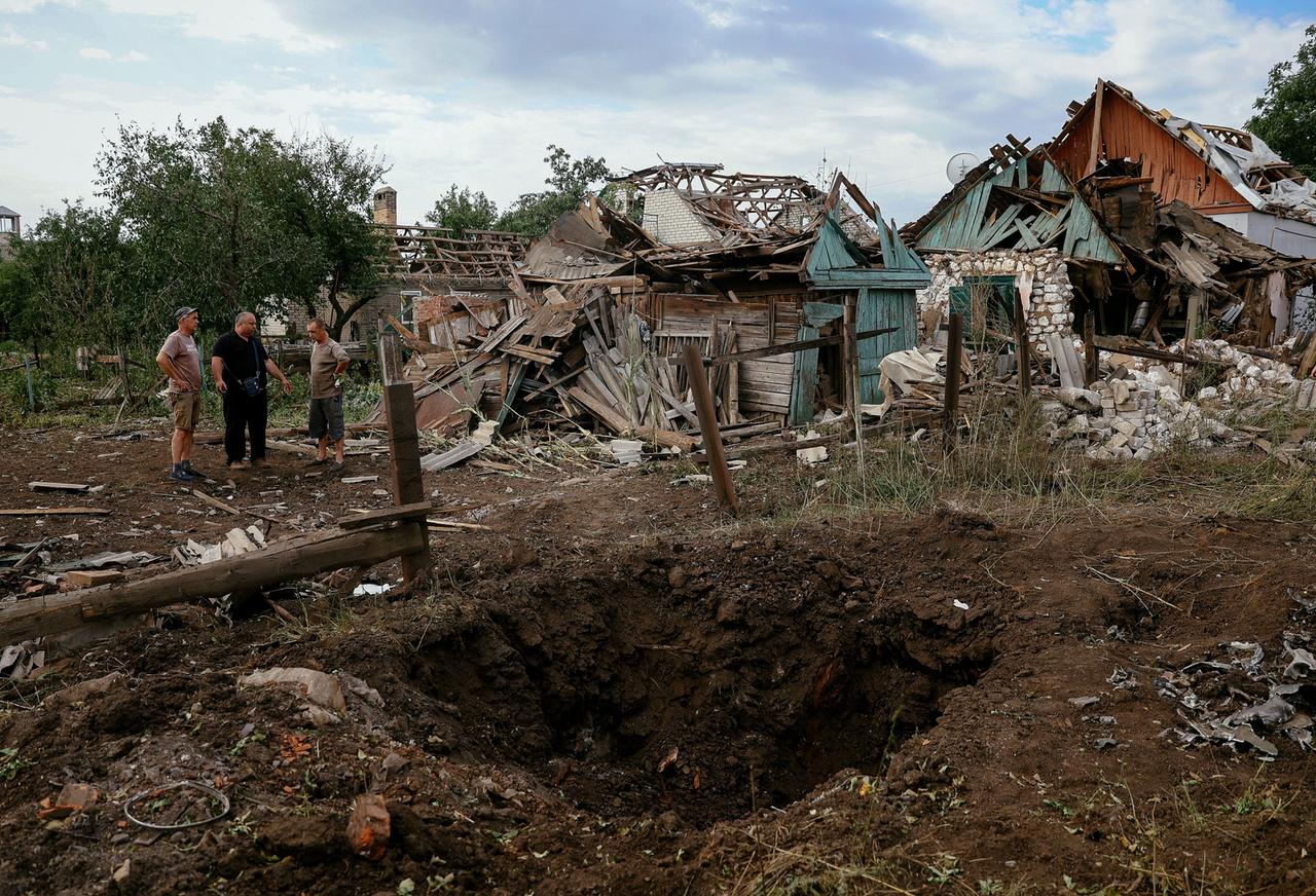 Einwohner stehen vor durch einen russischen Raketenangriff zerstörten Häusern in der Region Donezk in der Ukraine.