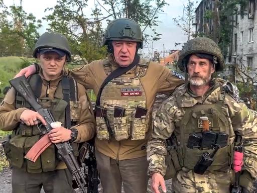 Der Gründer der Wagner Söldnertruppe Jewgeni Prigoschin steht mit zwei seiner Soldaten vor einem zerstörten Strassenzug inder ukrainischen Stadt Bachmut.
