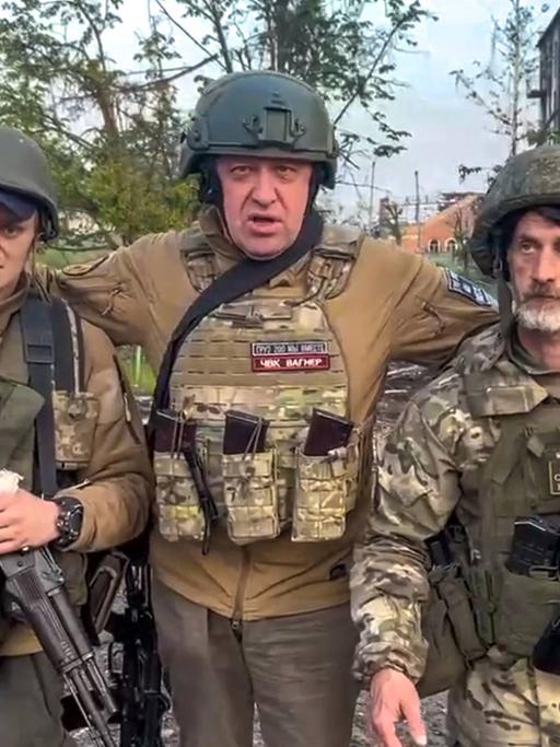 Der Gründer der Wagner Söldnertruppe Jewgeni Prigoschin steht mit zwei seiner Soldaten vor einem zerstörten Strassenzug inder ukrainischen Stadt Bachmut.