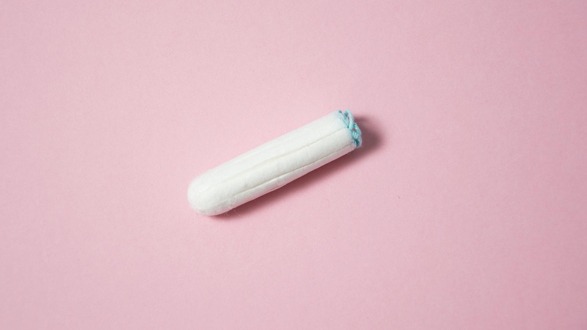 Ein weißer Tampon auf lachsfarbenem Hintergrund. Ein weißer Tampon auf lachsfarbenem Hintergrund.