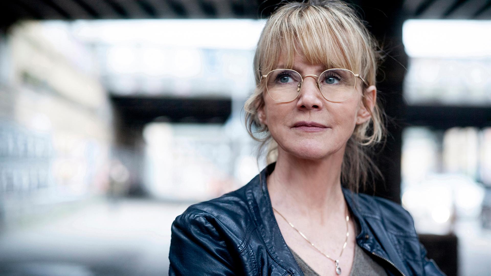 Eine Frau blickt nach links oben. Sie trägt eine Brille und ein graues Oberteil, dazu eine schwarze Jacke. Es ist die Schauspielerin Esther Esche. Eine Frau blickt nach links oben. Sie trägt eine Brille und ein graues Oberteil, dazu eine schwarze Jacke. Es ist die Schauspielerin Esther Esche.