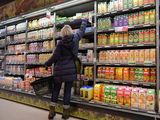 Eine Frau greift im Supermarkt in ein Kühlregal mit Säften