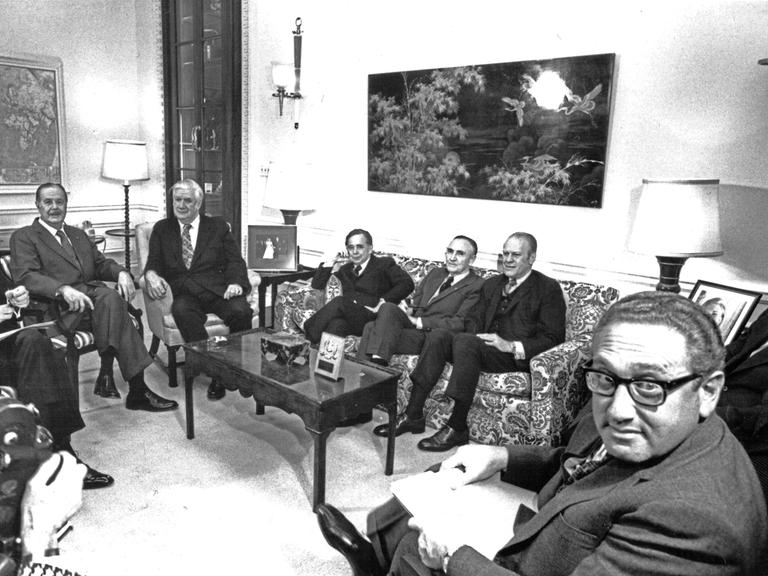 Gruppe von Politikern und Beratern, die um einen Tisch herum sitzen, Schwarz-Weiß-Aufname