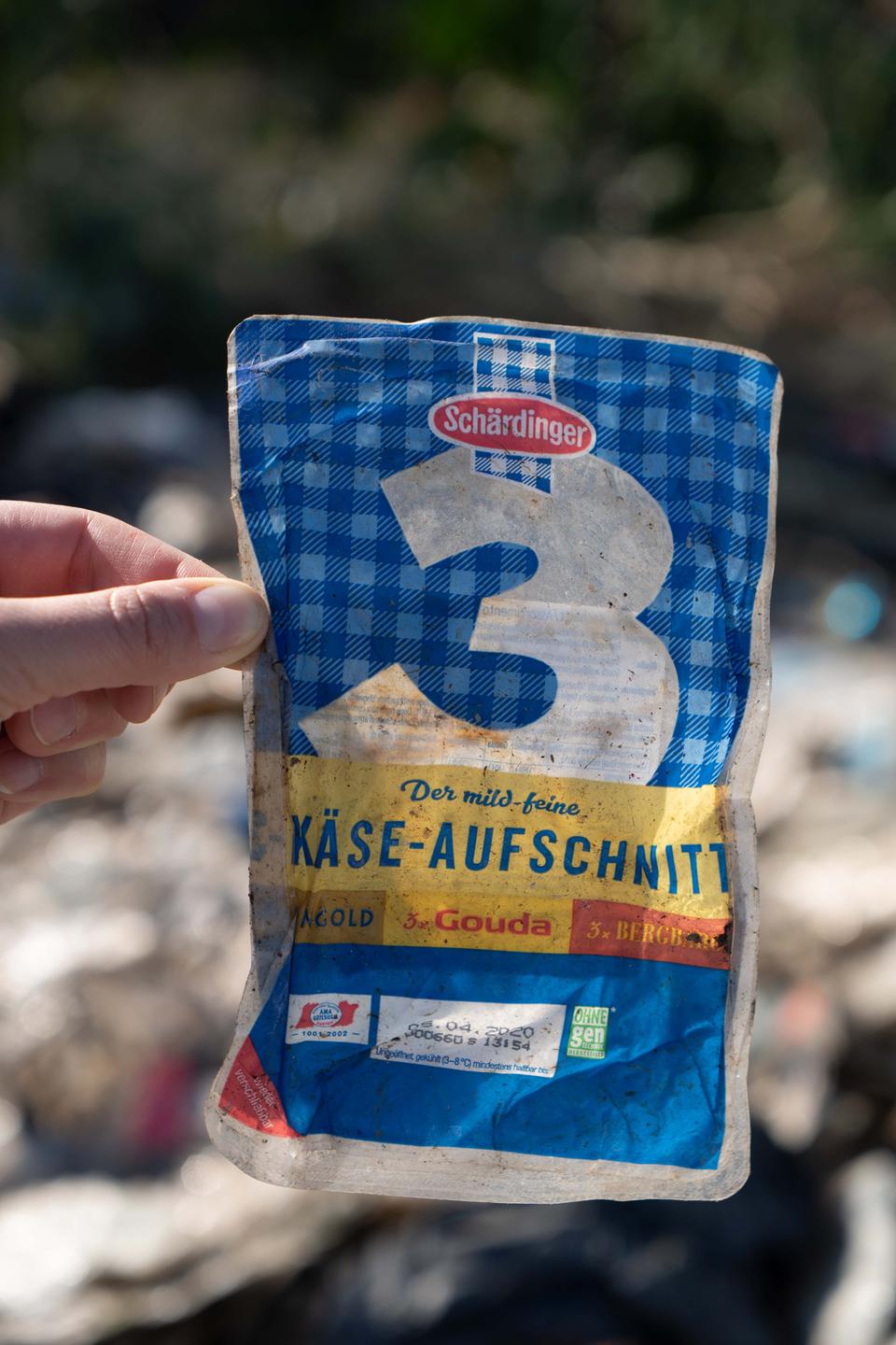 Eine Hand hält eine Käseaufschnitt-Tüte mit deutscher Aufschrift - gefunden auf einer Müllhalde in der Türkei.