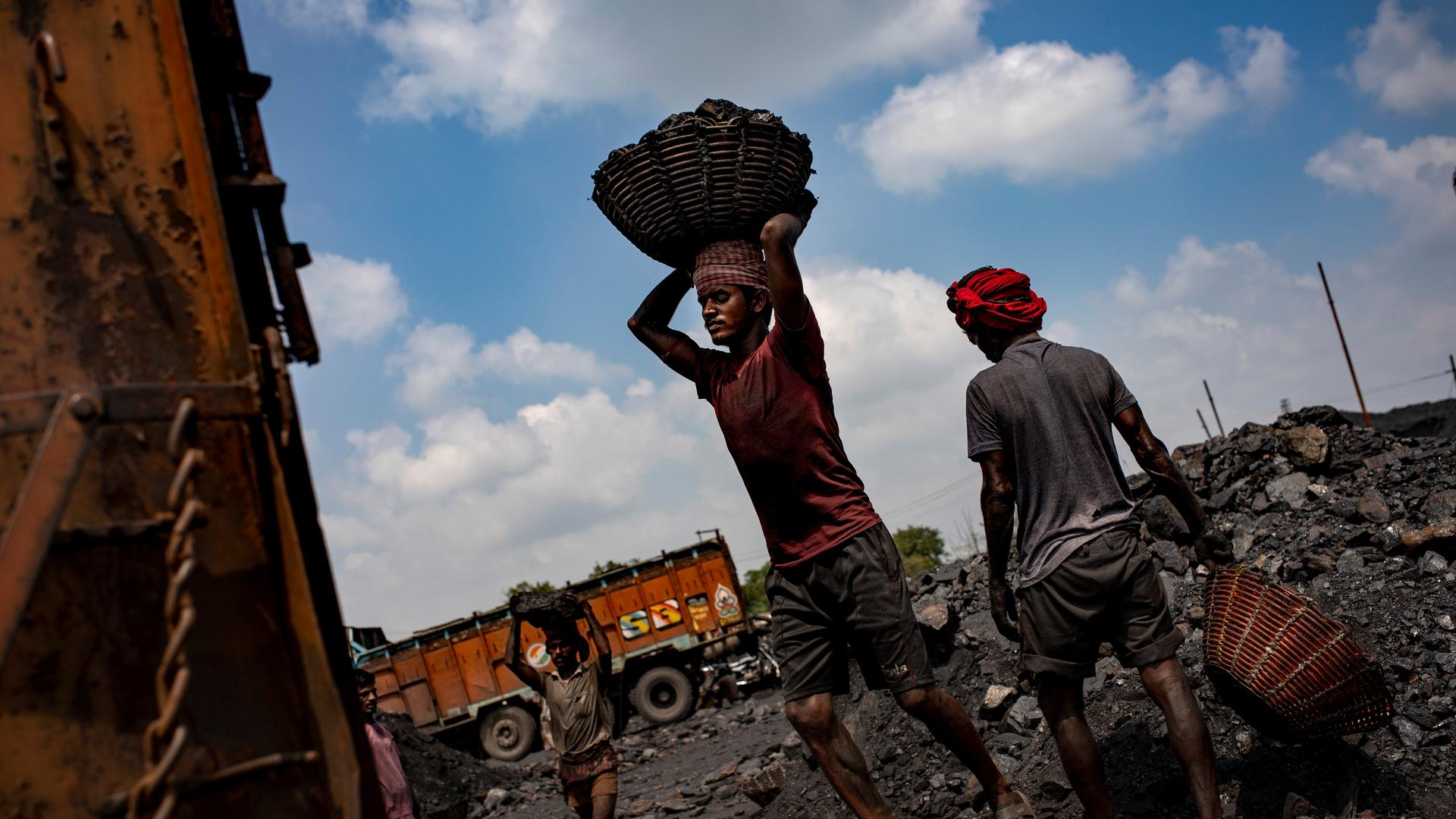 Verschmutzte Arbeiter tragen Kohle in einen LKW
