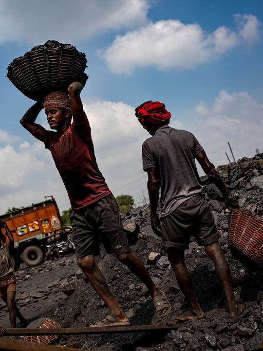 Verschmutzte Arbeiter tragen Kohle in einen LKW