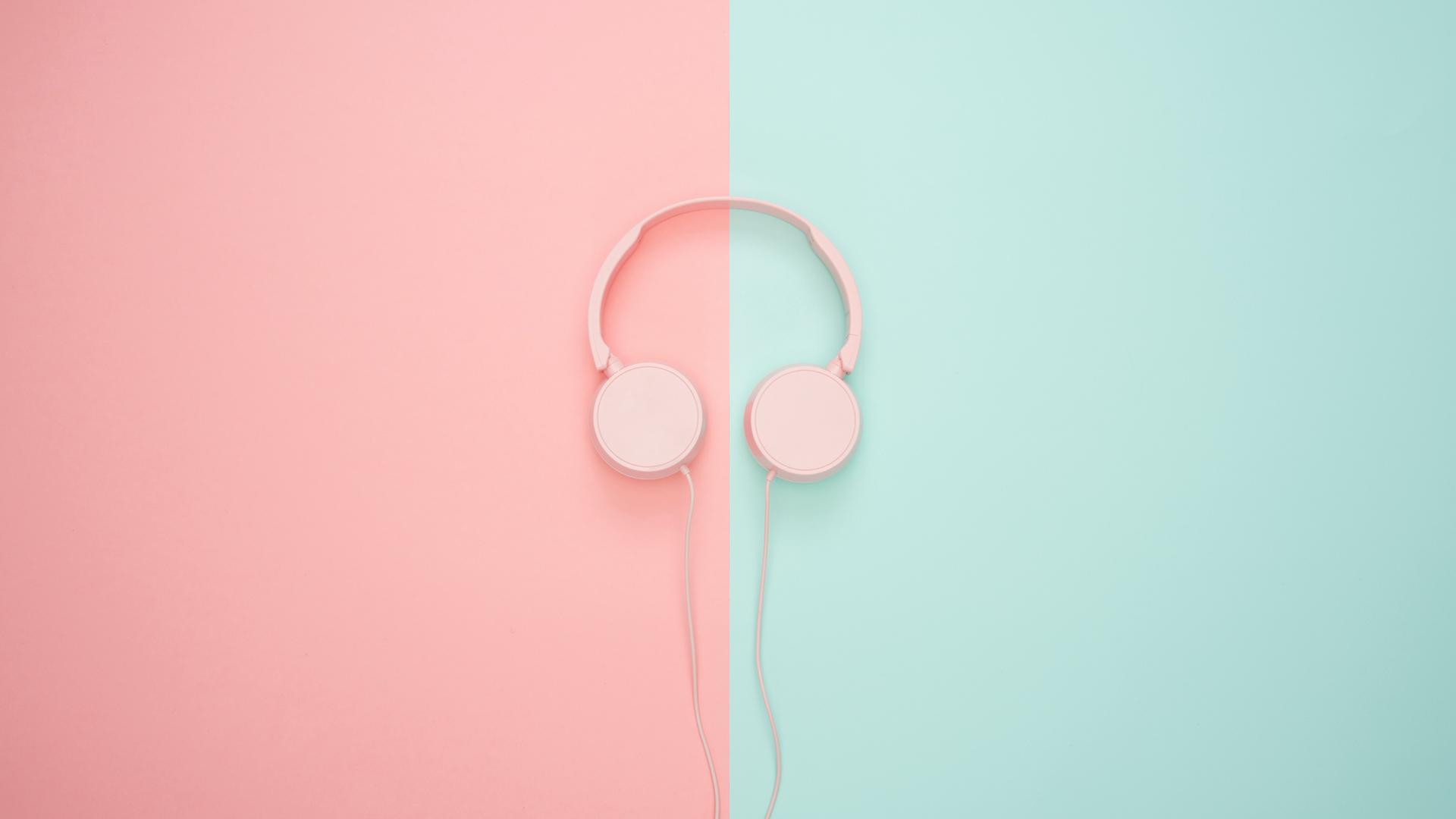 Ein Paar Kopfhörer liegen auf pink-türkisem Hintergrund. Ein Paar Kopfhörer liegen auf pink-türkisem Hintergrund.