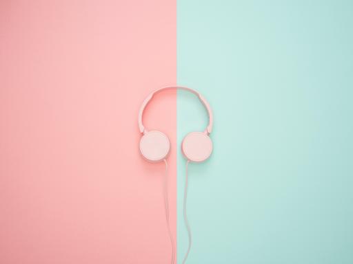 Ein Paar Kopfhörer liegen auf pink-türkisem Hintergrund.