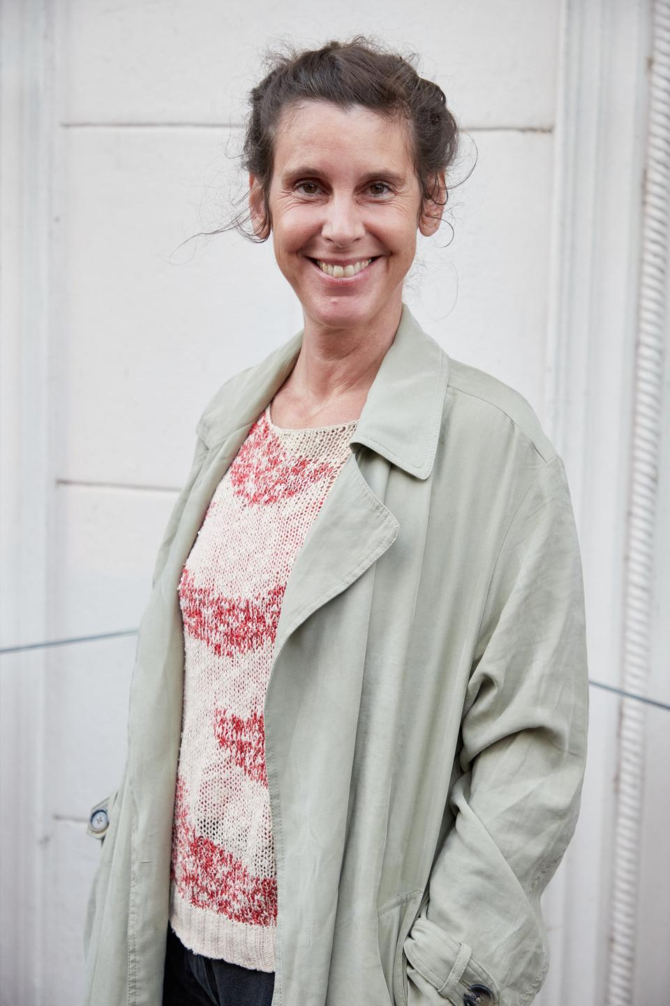 Daniela Dröscher, Autorin, steht auf einem Balkon. Die Mittvierzigerin trägt einen hellen Blazer und ein quergestreiftes Oberteil in Rot und Weiß darunter. Sie hat die Haare hochgesteckt, ihre Hände stecken in den Blazertaschen, sie lächelt in die Kamera. Daniela Dröscher, Autorin, steht auf einem Balkon. Die Mittvierzigerin trägt einen hellen Blazer und ein quergestreiftes Oberteil in Rot und Weiß darunter. Sie hat die Haare hochgesteckt, ihre Hände stecken in den Blazertaschen, sie lächelt in die Kamera.