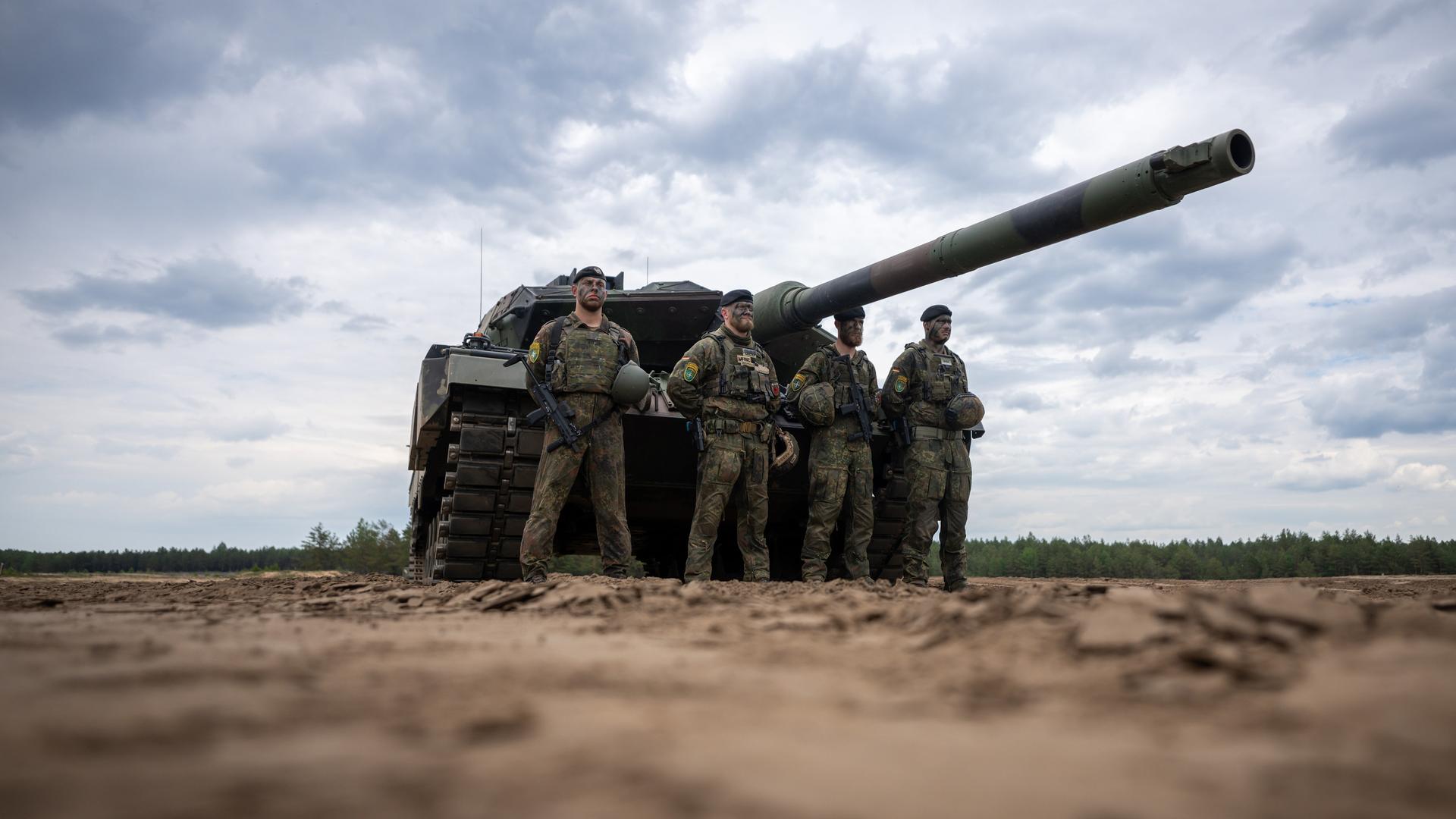 Vier Bundes-Wehr-Soldaten stehen vor einem Leopard-Panzer. Vier Bundes-Wehr-Soldaten stehen vor einem Leopard-Panzer.