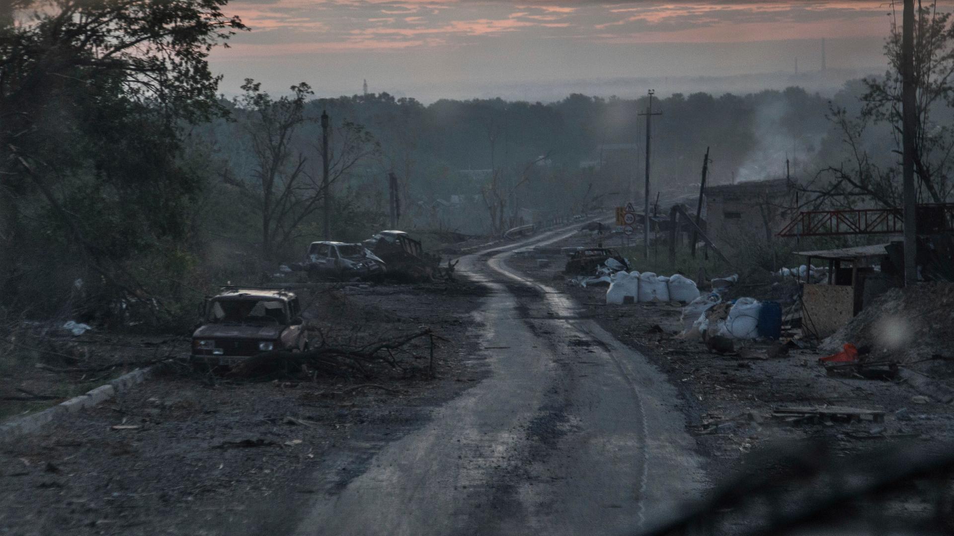 Während schwerer Kämpfe an der Front in Sjewjerodonezk in der Region Luhansk liegen ausgebrannte Autowracks am Rand eines Wegs.