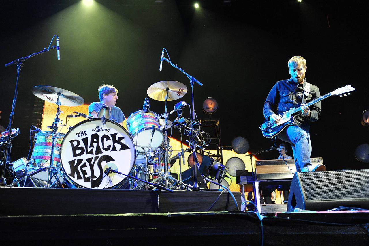 Der Schlagzeuger Patrick Carney und der Gitarrist und Sänger Dan Auerbach stehen spielend auf einer grell beleuchteten Bühne und agieren miteinander neben der Trommel mit dem Schriftzug "Black Keys". Der Schlagzeuger Patrick Carney und der Gitarrist und Sänger Dan Auerbach stehen spielend auf einer grell beleuchteten Bühne und agieren miteinander neben der Trommel mit dem Schriftzug "Black Keys".