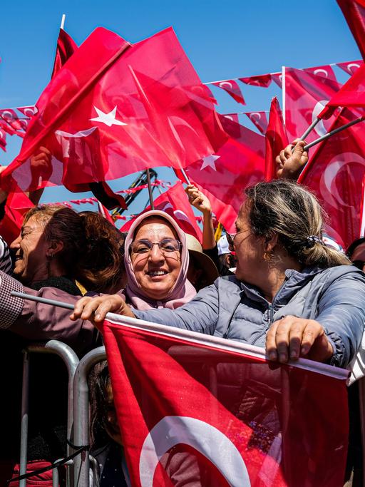 Ein Meer roter Fahnen mit zwei Frauen im Vordergrund bei einer Wahlveranstaltung n der Türkei 