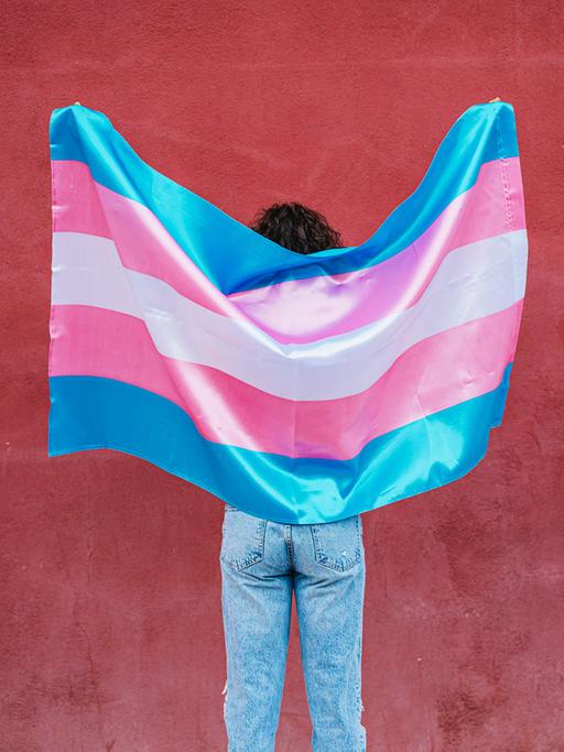 Eine Person hält eine Transgenderflagge.