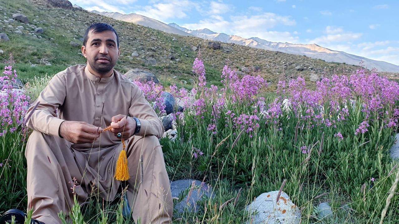 Der Übersetzer Jawed Haqmal in Afghanistan vor einer blühenden Wiese mit einer Berglandschaft im Hintergrund. Der Übersetzer Jawed Haqmal in Afghanistan vor einer blühenden Wiese mit einer Berglandschaft im Hintergrund.