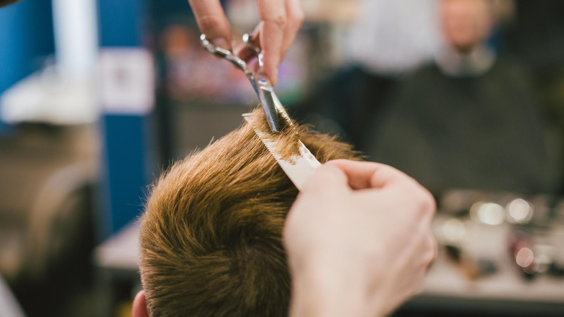 Eine Friseur schneidet einer Person die Haare. 