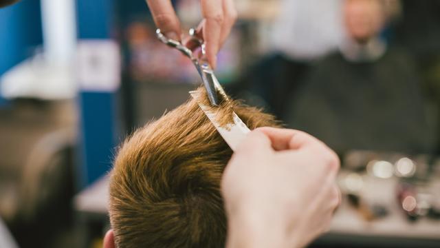 Eine Friseur schneidet einer Person die Haare. 